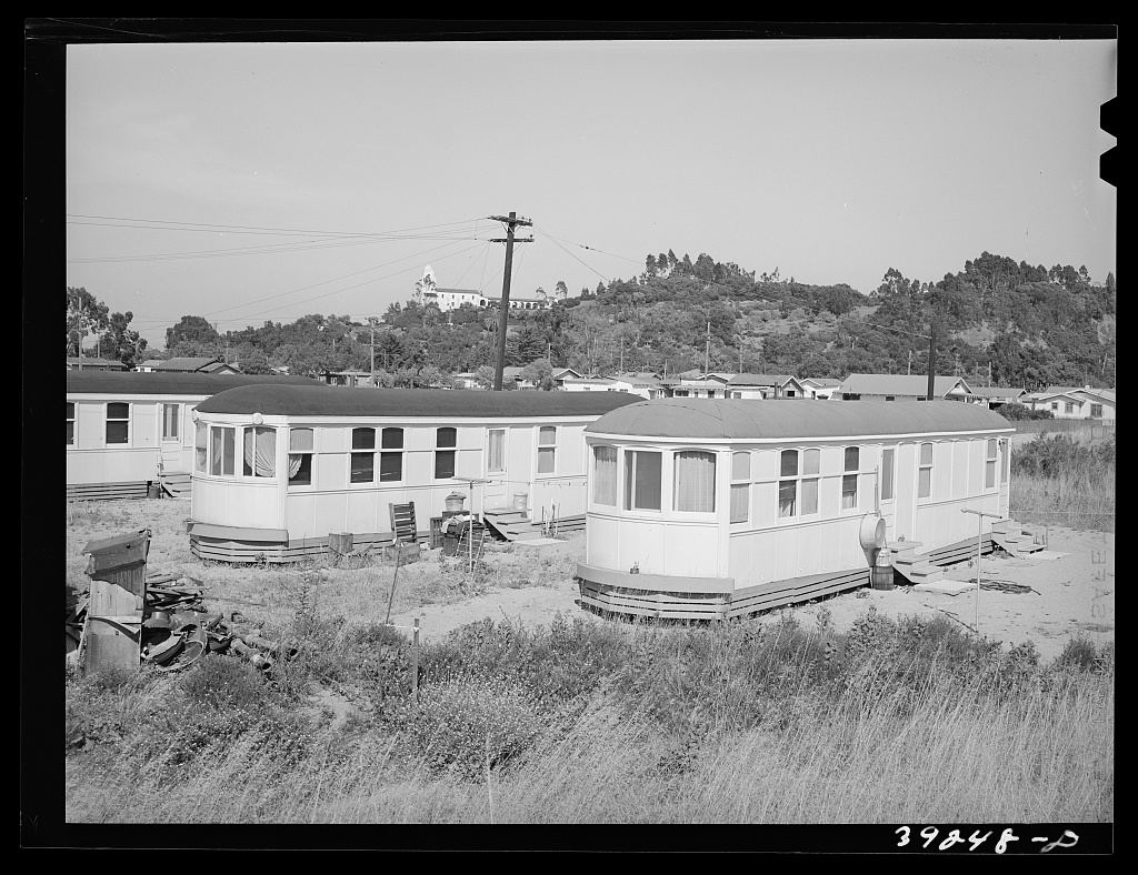 Two retired streetcars standing in open scrub on the edge of San
                  Diego, converted into homes, with washing lines and steps built up
                  to their doors.